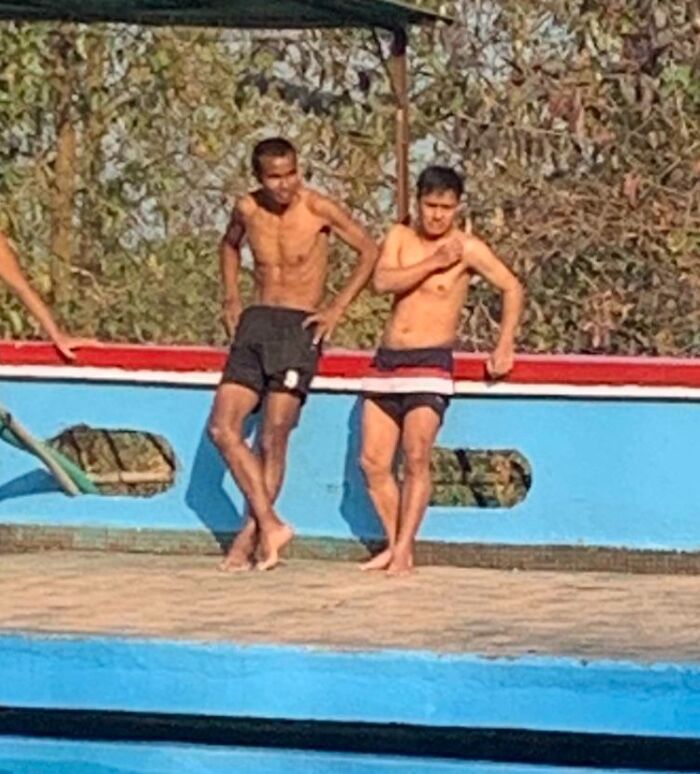 Two boys in swimwear standing near a pool, their shorts matching the colors of the pool surroundings perfectly.