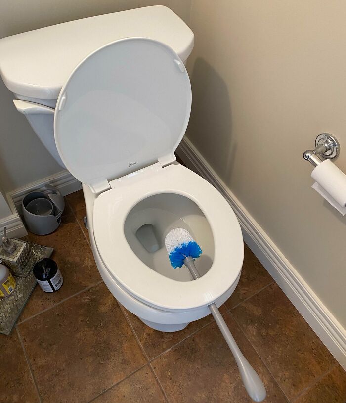 Toilet with brush inside the bowl showing a genius life hack for easy bathroom cleaning and maintenance.