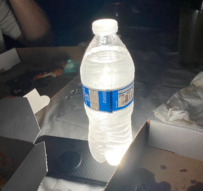 Plastic water bottle placed on top of a smartphone used as a light source, showcasing a genius life hack in everyday use.