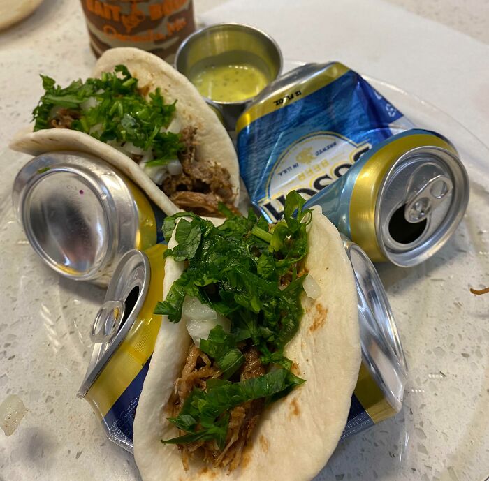 Tacos held upright by crushed soda cans, demonstrating a genius life hack for easy taco assembly and serving.