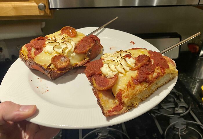 Two slices of pepperoni pizza with piped mashed potatoes on top, held on a white plate, demonstrating genius life hacks.