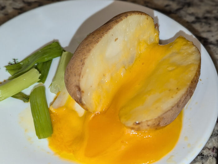 Half potato filled with bright melted cheese with celery on a plate, showcasing restaurant workers' unusual food orders.