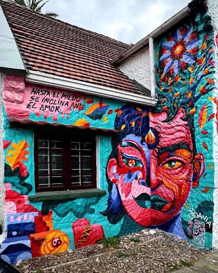 Colorful mural blending fantasy and reality by Colombian artist SakoAsko on an exterior building wall near a window.