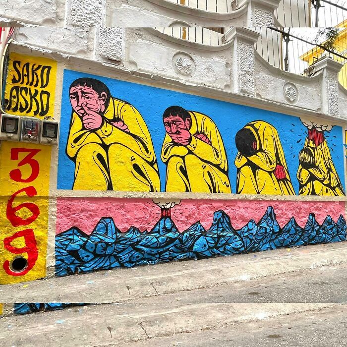 Mural by Colombian artist SakoAsko depicting surreal yellow figures blending fantasy and reality on a colorful urban wall.