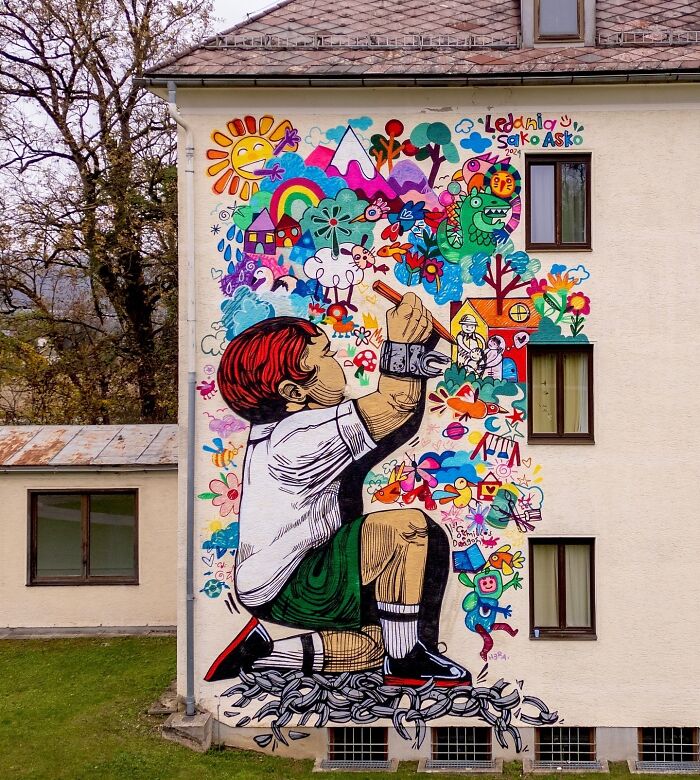 Colorful mural by Colombian artist SakoAsko depicting a child drawing fantastical creatures and scenes on a building wall.