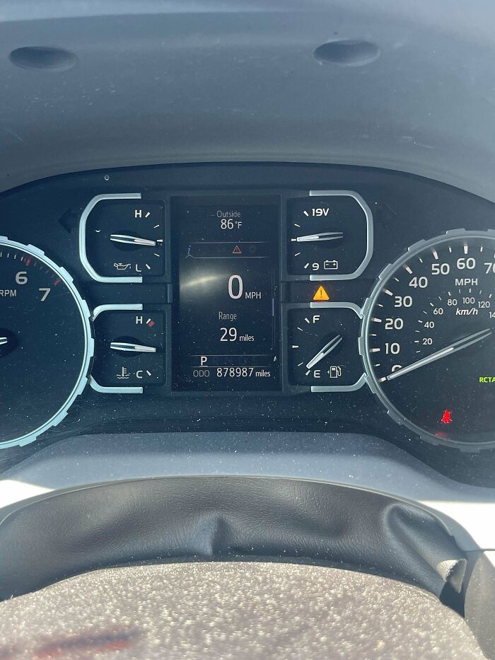 Car mechanic photo of dashboard showing high mileage odometer at 878987 miles with warning lights on and fuel range 29 miles.