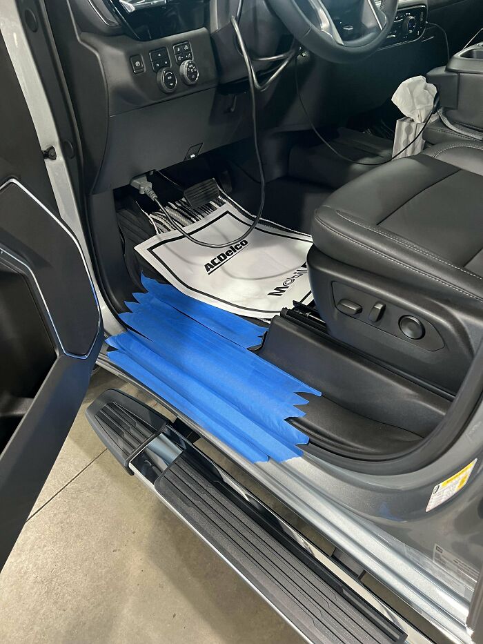 Car mechanic's photo showing blue tape on truck door sill to highlight a repair detail inside the vehicle.