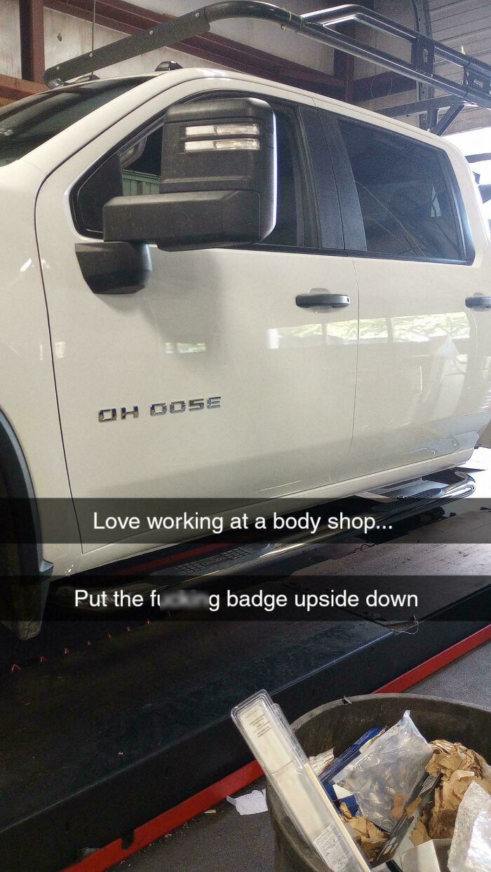 White truck at a mechanic's shop with an upside-down badge leaving customers and mechanics speechless.