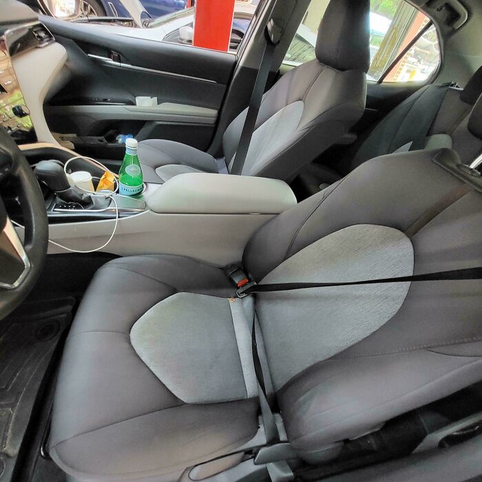 Car mechanic’s photo showing a broken seatbelt twisted unusually on the passenger seat inside a modern vehicle.