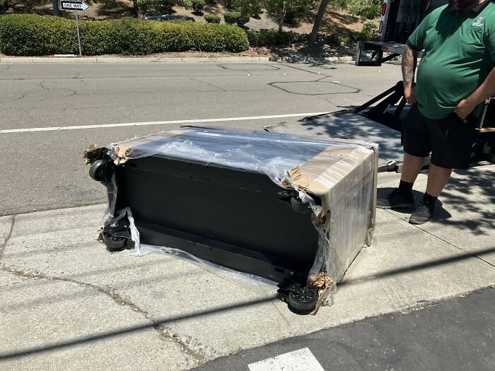 Car mechanic photo of a damaged part wrapped in plastic on the sidewalk to show unusual repair situation.