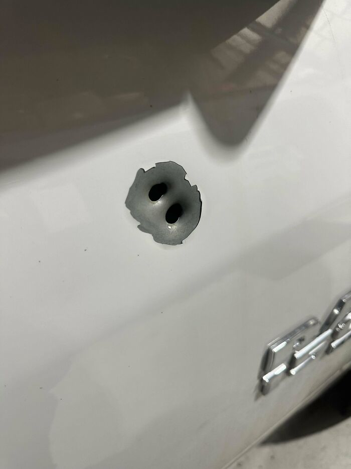 Close-up of damaged car body with two small holes showing what car mechanics captured to prove the issue.