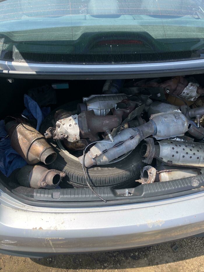 Car mechanics showing a trunk full of used catalytic converters to prove their findings for repair or replacement.