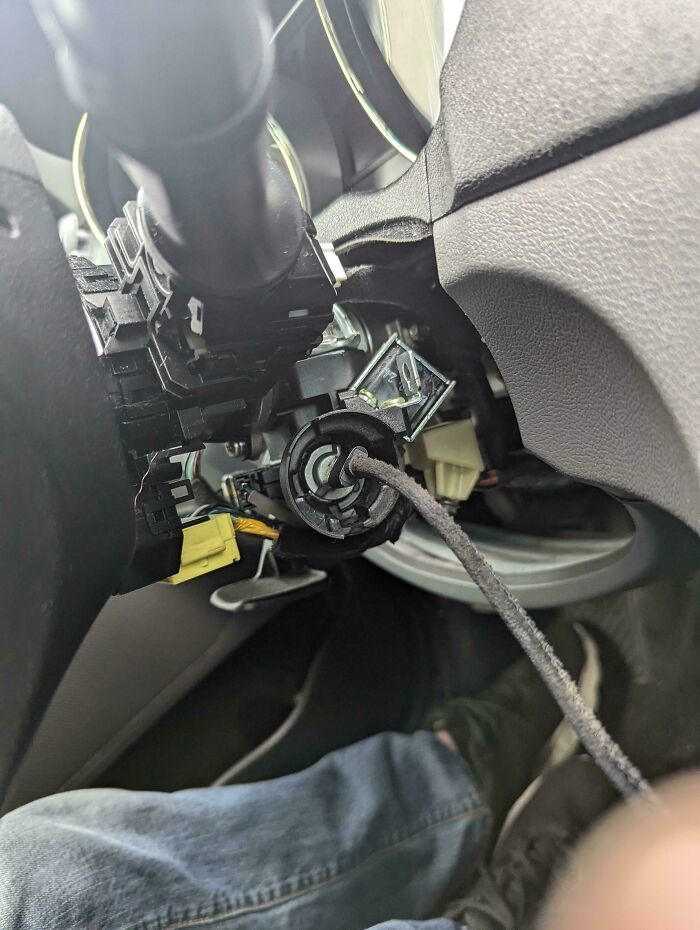Car mechanic taking a close-up photo of unusual wiring inside the vehicle dashboard to show the problem clearly.