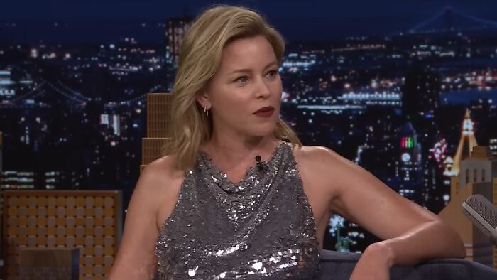 Actress in a sparkly top speaking on a late-night talk show, illustrating celebrity entitlement about work and life.