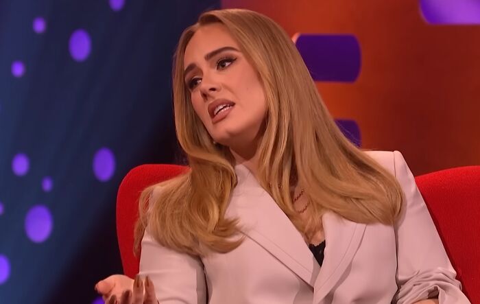 Celebrity woman with long blonde hair in a white blazer speaking during a talk show about work and life entitlement.