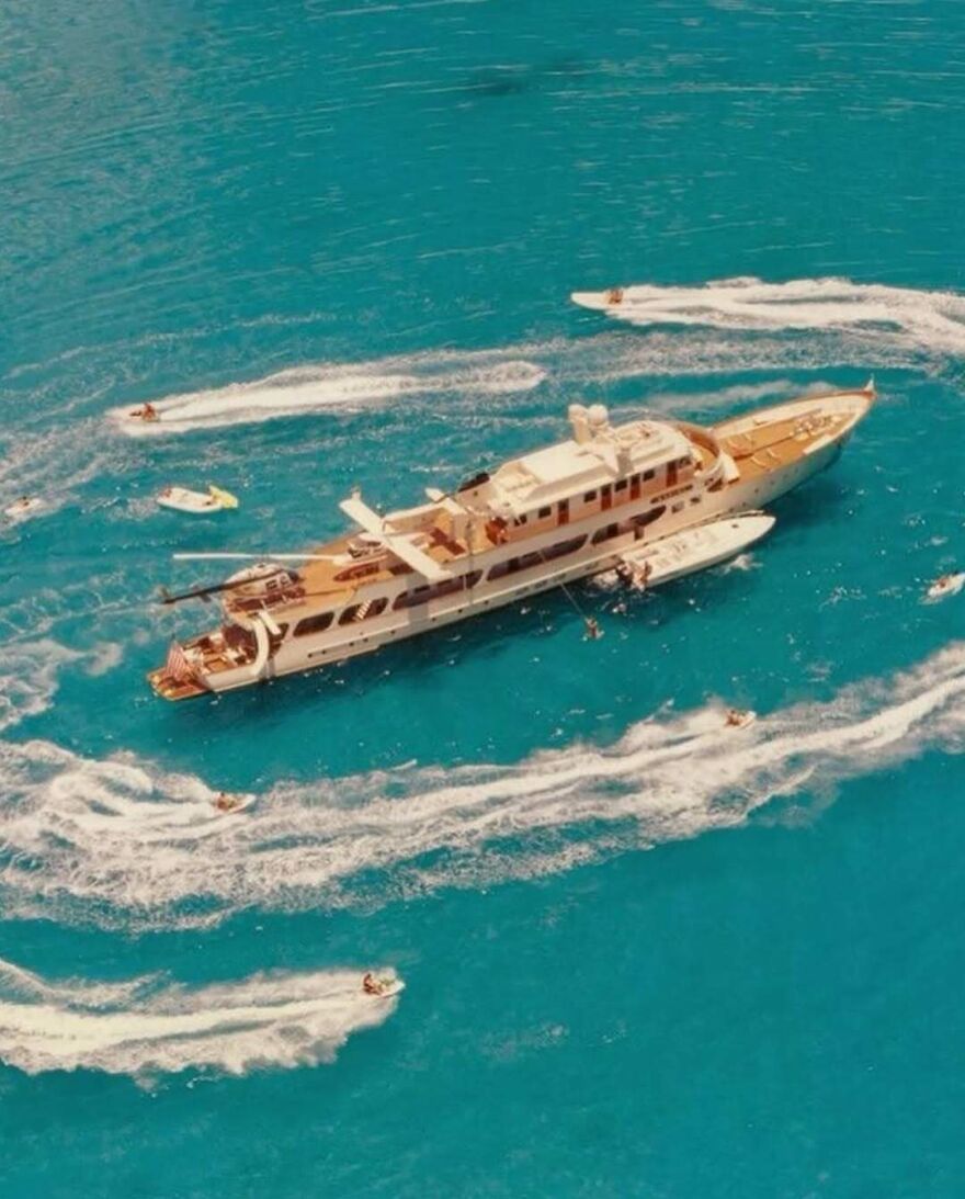 Luxury yacht surrounded by jet skis in bright blue water representing Jordan Belfort&rsquo;s financial reality in 2025.
