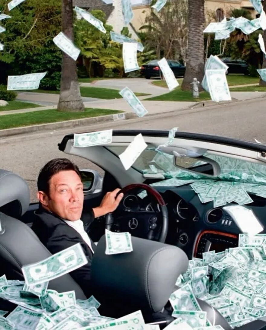 Man in luxury car surrounded by flying money, illustrating Jordan Belfort&rsquo;s financial reality and debt in 2025.