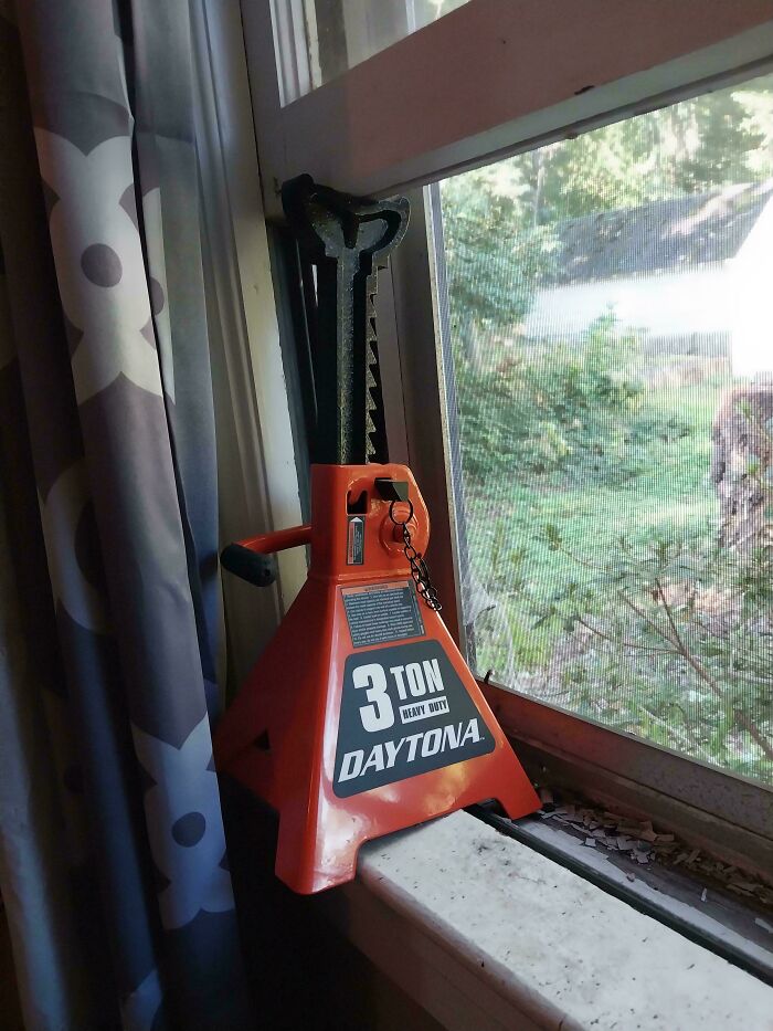Heavy duty 3 ton jack ingeniously repurposed as a window prop by redneck engineers.