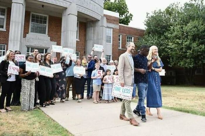 Amazing Photos - crowd outside brick building holding signs, smiling and cheering as a couple walks by in a celebratory scene