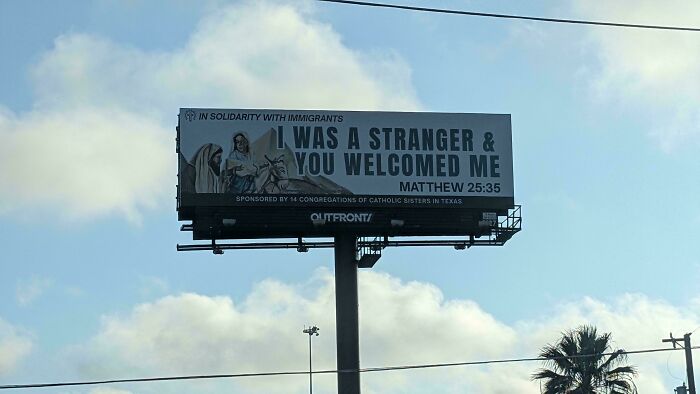 Billboard showing a message of solidarity with immigrants, reflecting chaotic good actions towards strangers and kindness.
