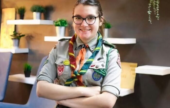 Young woman scout smiling confidently indoors, representing heartwarming posts and positive news for uplifting moments.