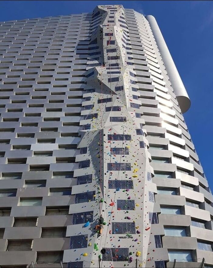 Modern Danish prison cell exterior featuring a unique climbing wall on a high-rise building under clear blue sky.