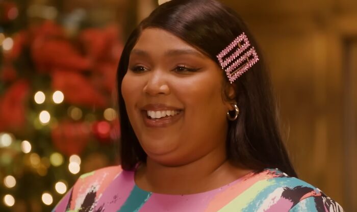 Smiling woman with a pink hair clip, illustrating moments celebrities show entitlement in work and life discussions.