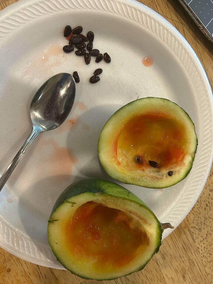 Half-cut small tomato with seeds on a paper plate, illustrating nature's playful garden surprises and odd fruit sizes.