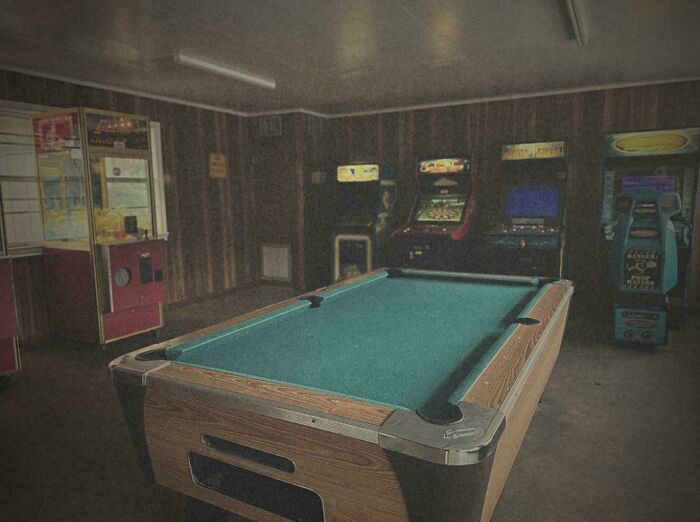 Vintage arcade and pool table in a dimly lit room evoking ’90s posts and nostalgic memories of that era.