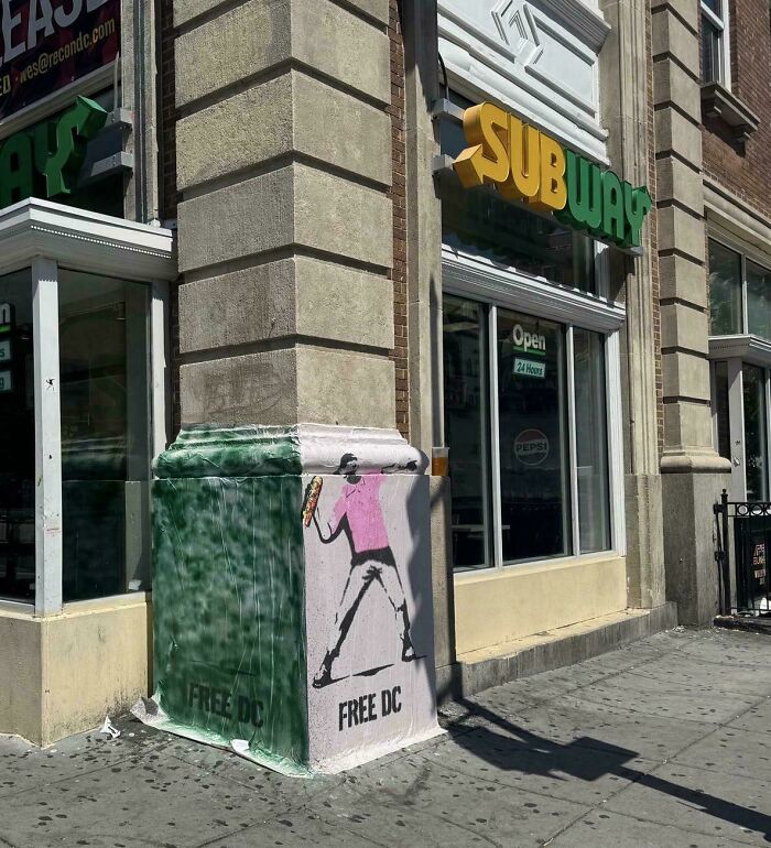 Street art on a city building corner showing a person throwing a sandwich, highlighting chaotic good actions in urban settings.