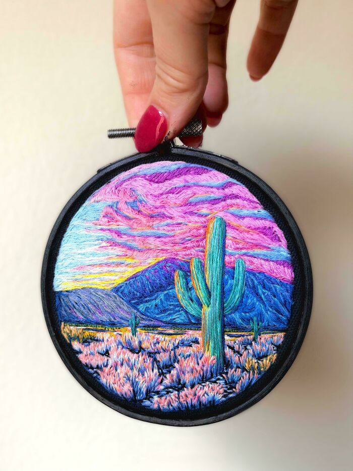 A vibrant embroidery creation depicting a desert sunset with a saguaro cactus, mountains, and colorful sky, inspiring embroidery.