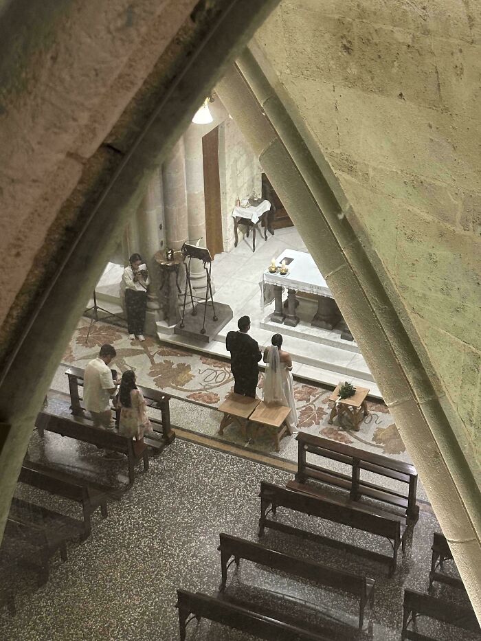 Couple at wedding altar with guests in church, captured from above creating an accidental Renaissance photo moment.