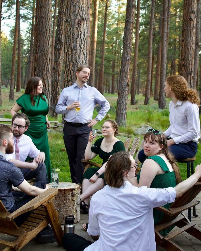 Group of people socializing outdoors in a forest setting, captured in an accidental Renaissance style photo.