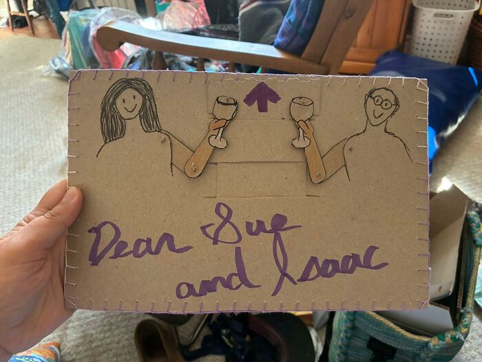 Handmade cardboard craft project with stick-figure drawings holding wine glasses, an example of DIY craft shaming fail.