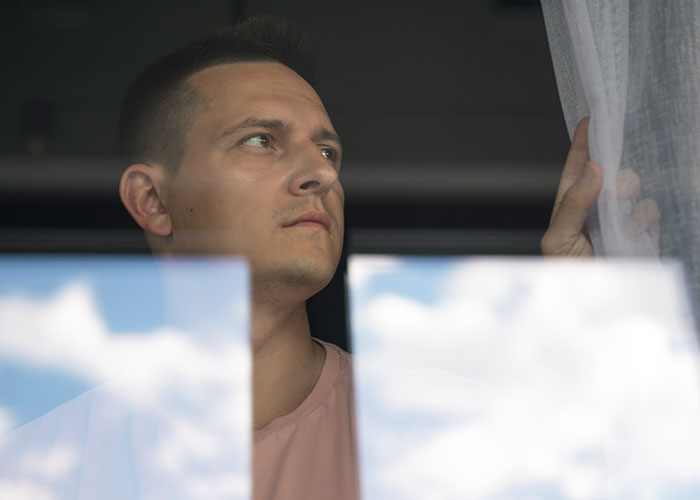 Man looking thoughtfully out a window, reflecting on getting sick after eating food his dad has touched.