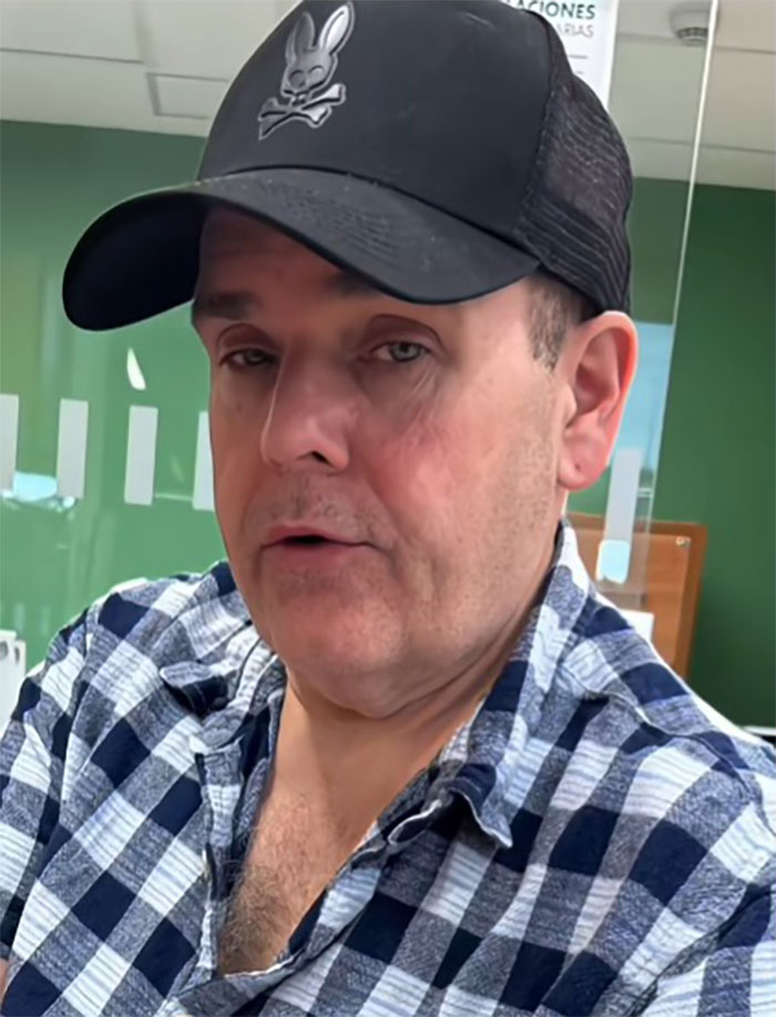 Man wearing black cap and checkered shirt sharing his facelift experience in Mexico in an indoor setting with green walls. Man wearing black cap and checkered shirt sharing his facelift experience in Mexico in an indoor setting with green walls.