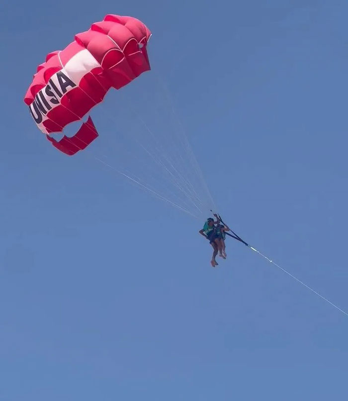 Parasailing with a red parachute against clear sky, illustrating mid-air assault during parasailing incident. - 4