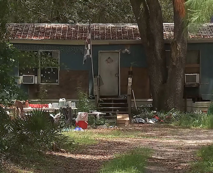 Abandoned Florida home with boarded windows and overgrown yard where mother left child and seven dogs for two weeks.