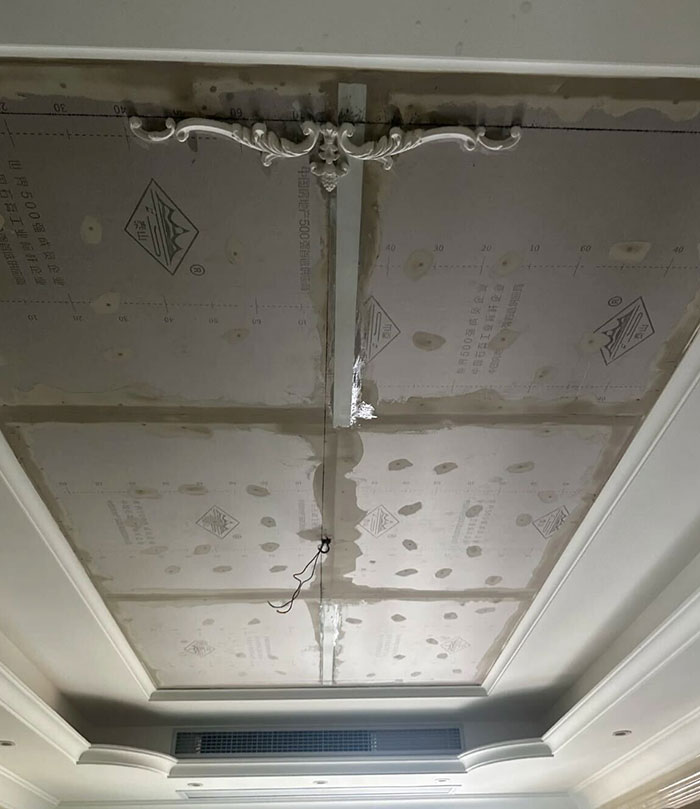 Ceiling under construction with damaged glass ceiling and chandelier area after angry boy incident.