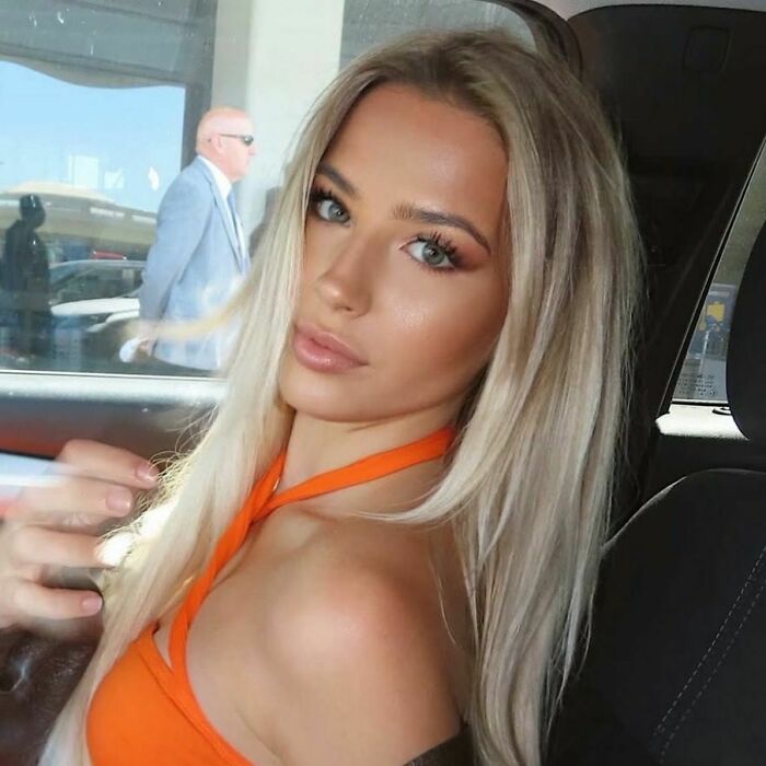 Young woman in an orange top sitting in a car, sharing her story about accidentally leaving a tampon inside for a month.