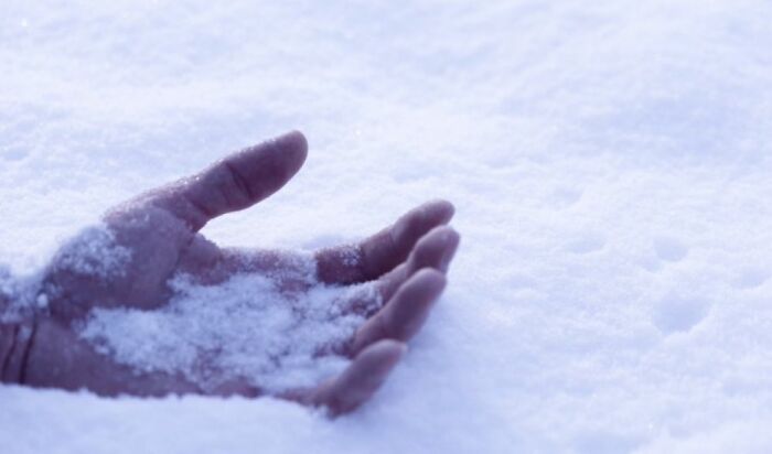 A hand partially buried in snow, creating an unsettling image related to morbid knowledge and eerie visuals.