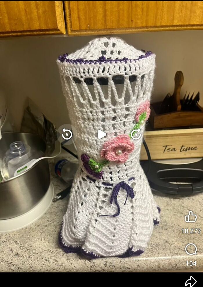 Crocheted DIY project cover on a kitchen appliance with floral decorations, showcasing craft shaming fail.