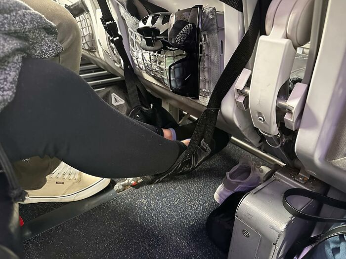 Footrest hammock strap attached under airplane seat, showcasing one of the brilliant Amazon finds for travel comfort and convenience.