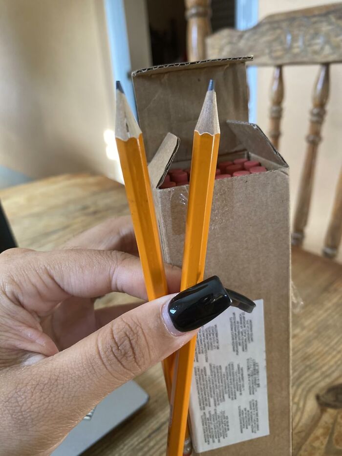 Hand holding two sharpened yellow pencils in front of an open box of pencils, showcasing back to school finds.