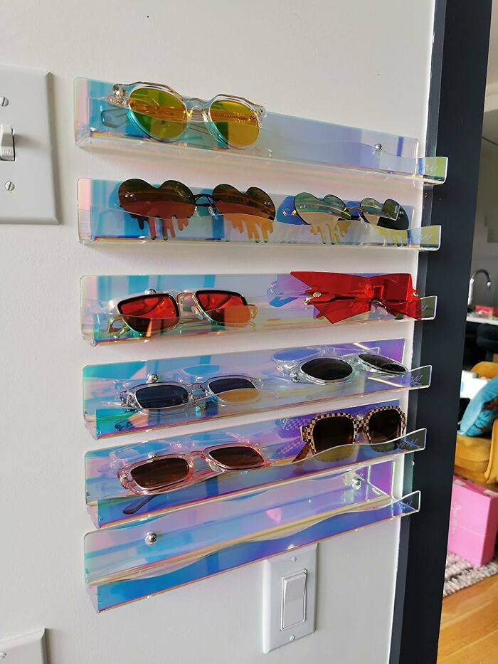 Iridescent wall-mounted decor item used to neatly store and display multiple pairs of sunglasses in a modern space