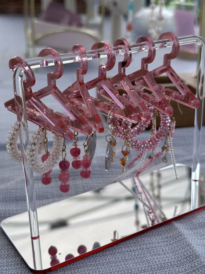 Clear pink mini hangers used as jewelry holders for earrings and bracelets, showcasing everyday items with a personality upgrade.