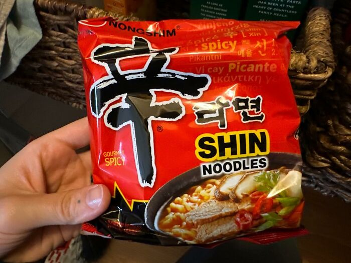 Hand holding a pack of spicy Shin noodles, a dorm kitchen essential for quick and easy meals beyond cereal.