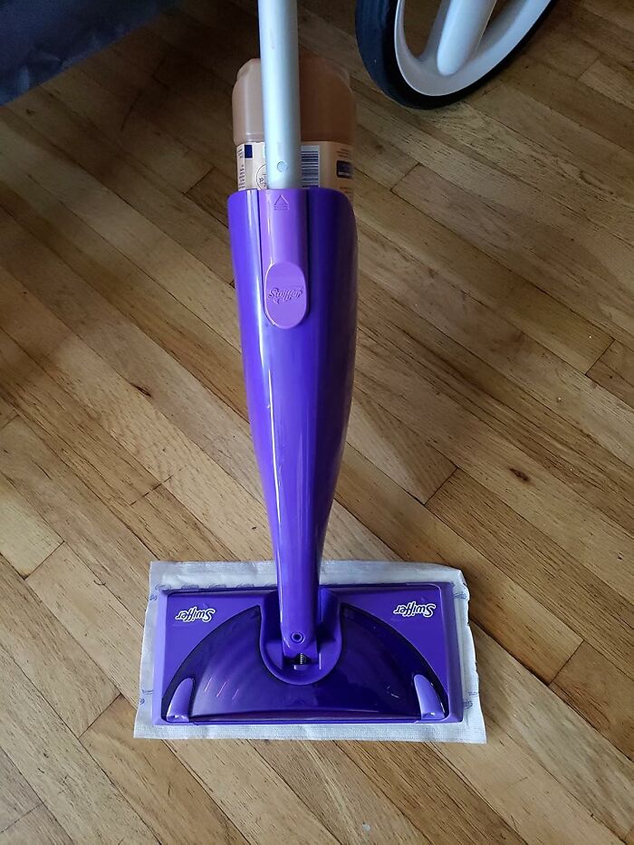 Purple Swiffer mop on wooden floor as a practical dorm find to help survive freshman year and beyond.