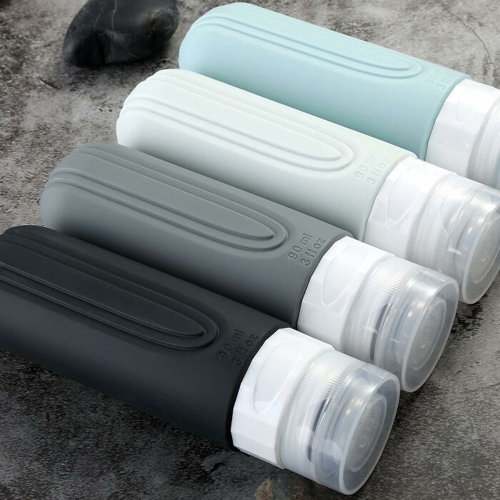 Silicone travel bottles in black, gray, white, and blue, ideal travel finds for people bad at packing efficiently.