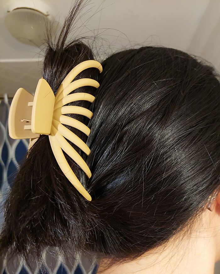 Close-up of a durable beige hair claw clip securing dark hair, showcasing a long-lasting everyday hair accessory.